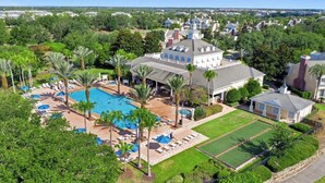 An aerial view of a resort with a swimming pool, sun loungers, and a well-maintained lawn. - Luxury Condo with Amazing Views Near Attractions (Kissimmee)