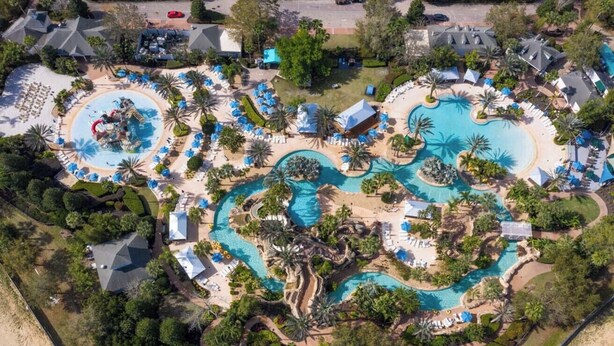 An aerial view of a resort with multiple swimming pools, sun loungers, and palm trees. - Luxury Condo with Amazing Views Near Attractions (Kissimmee)