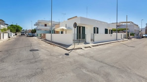 A modern white building with a small entrance and a covered outdoor seating area.