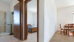 A room with a shower, a bed, and a dining area with chairs and a table.