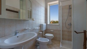 A bathroom with a sink, bidet, toilet, and a glass-enclosed shower.
