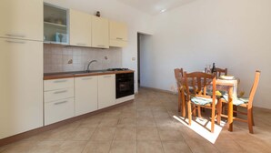 A compact kitchen with a stove, oven, and sink, adjacent to a dining area with a table and chairs.
