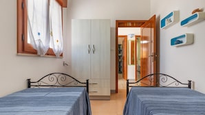 Une chambre avec deux lits, une armoire et une salle de bain visible à travers une porte ouverte.