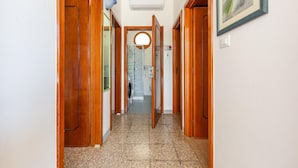 Un couloir avec des portes en bois, un sol carrelé et un tableau encadré accroché au mur.