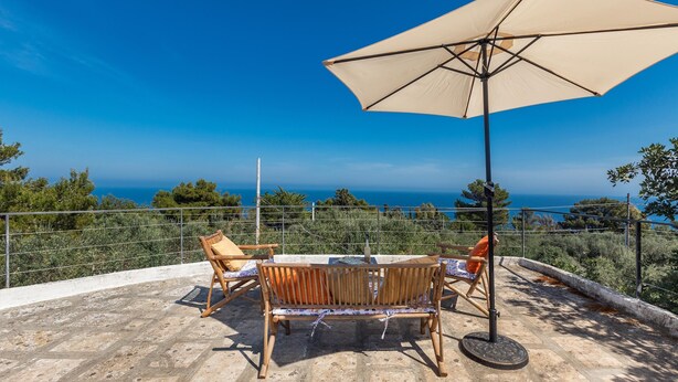 Un espace extérieur aménagé avec un banc et des chaises en bois, une table et un grand parasol.