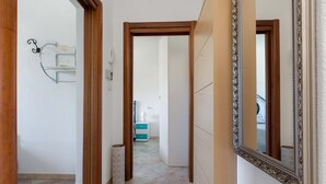 A hallway with a wooden door frame, a mirror with an ornate frame, and a small trash bin. - 2518 Villa del Cavaliere by Barbarhouse (Castrignano del Capo)