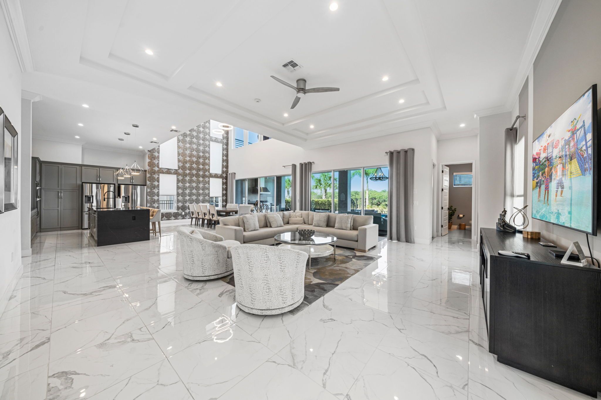 A spacious living area with a modern kitchen, a large sofa set, and a flat-screen TV.