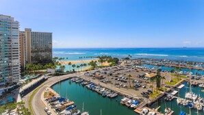 A marina with boats docked, a beach, and high-rise buildings in the background. - Ilikai Marina #1780, Beautiful Ocean, Sunset and Harbor views! (Honolulu)