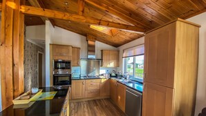 Uma cozinha moderna com armários de madeira, bancada preta, eletrodomésticos de aço inoxidável e uma janela com vista para o exterior.