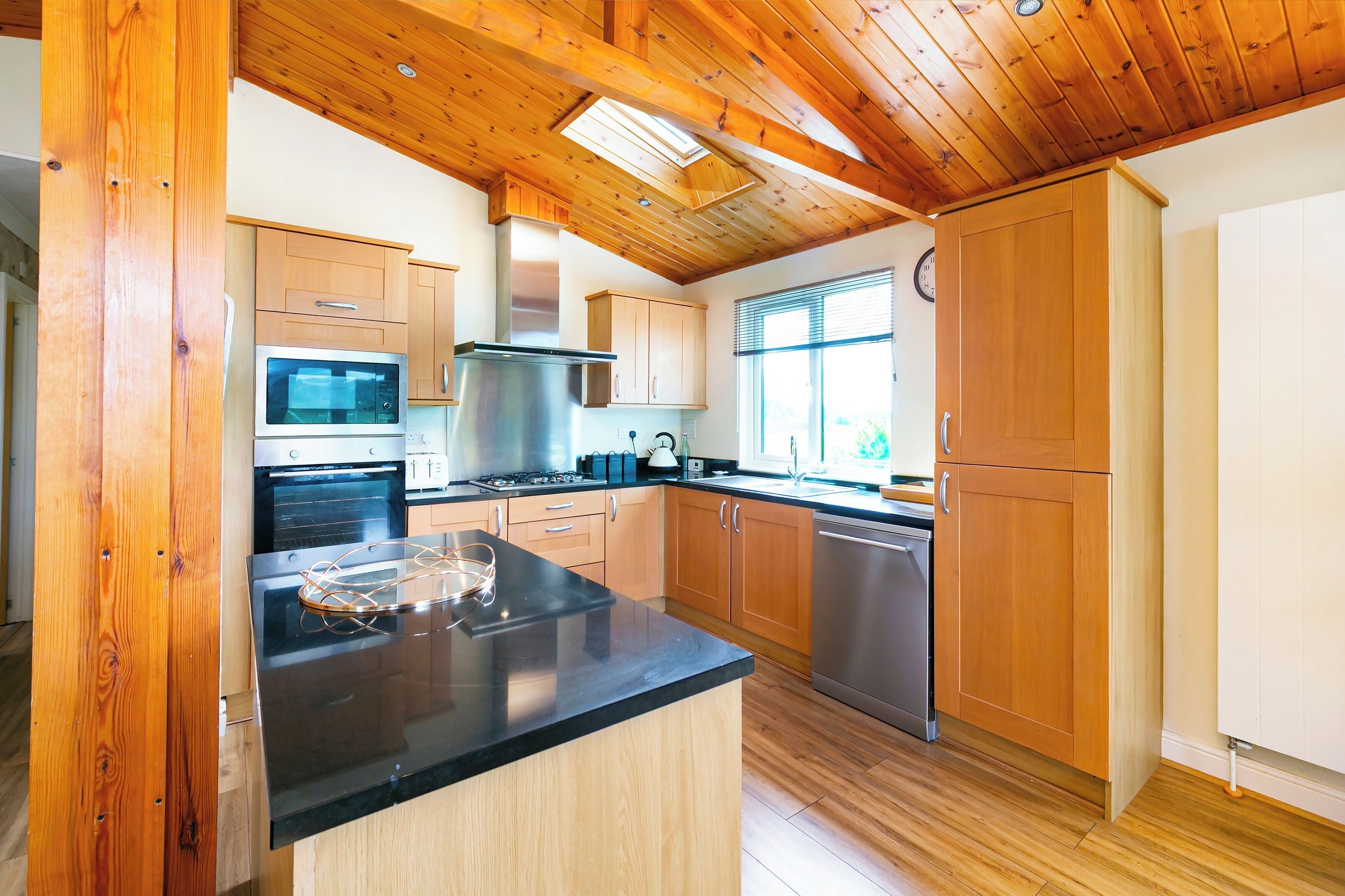 A modern kitchen with wooden cabinets, stainless steel appliances, and a black countertop.