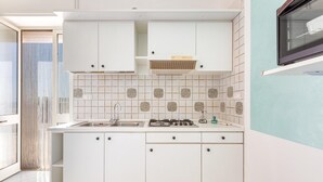 Uma cozinha moderna com armários brancos, fogão a gás e pia.