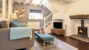 A cozy living room with a sofa, ottoman, and a fireplace. - 3 Ivy Court (Dolgellau)