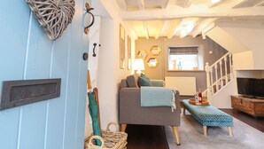 A cozy living room with a sofa, a bench, a wicker basket, and a wall-mounted heart decoration. - 3 Ivy Court (Dolgellau)