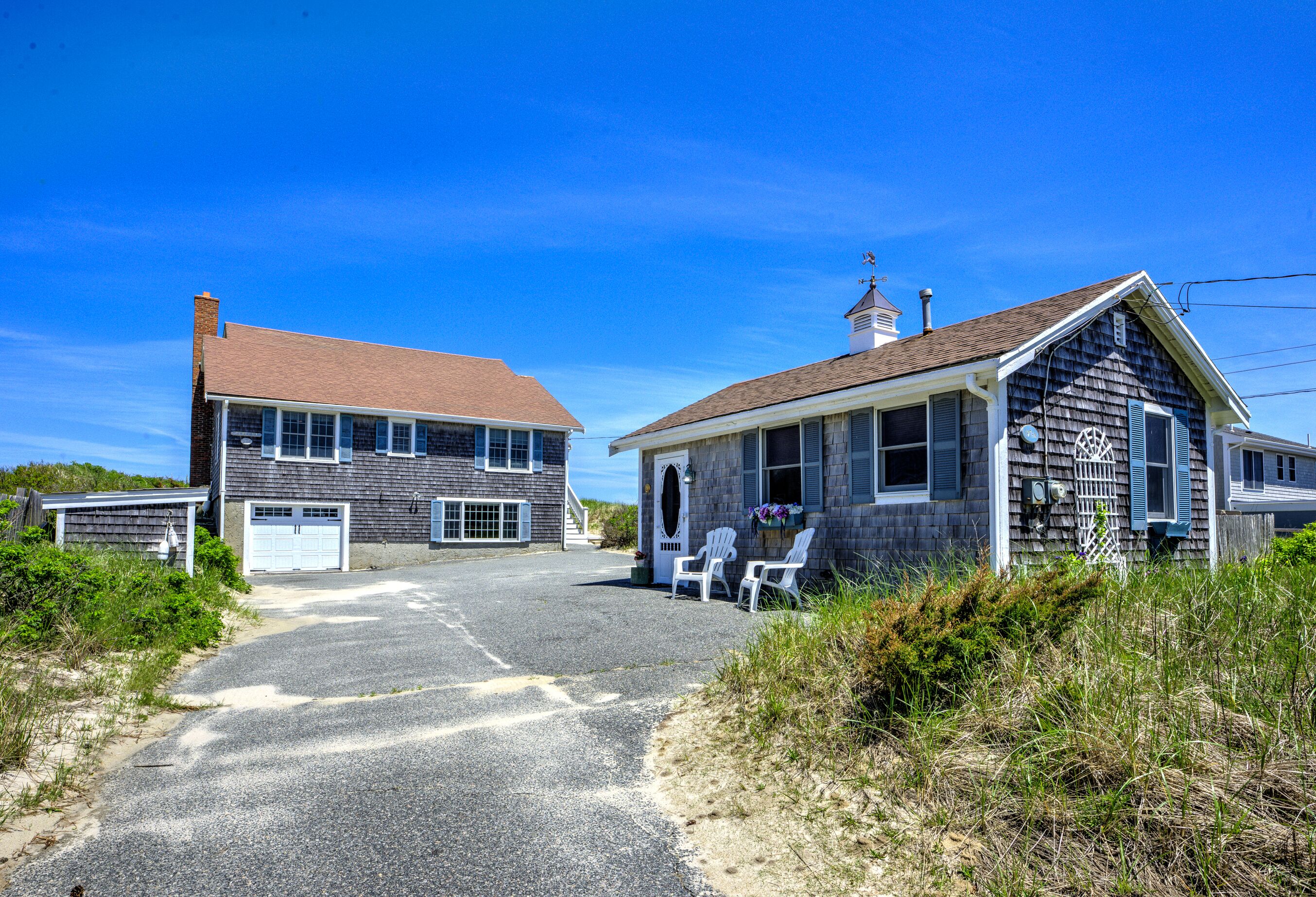 A two-story building with a garage, a small porch with chairs, and a visible chimney.