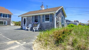 A small, single-story building with a porch and two white chairs.