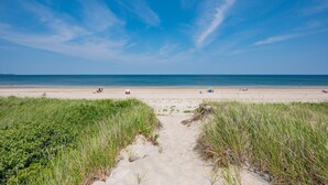 Un sentiero sulla spiaggia che conduce verso l'oceano, con persone visibili in lontananza.