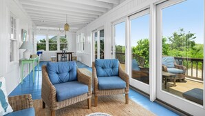 A covered porch with wicker furniture, a table, and chairs. - Sagamore Oceanfront Cottage—Decks & Sunsets (Bourne)