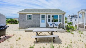 A beachfront cottage with a deck, a barbecue grill, and a picnic table. - Cape Cod Water View Cottage—Steps to Private Beach (East Sandwich)