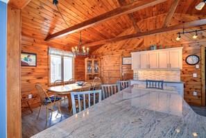 A wooden cabin interior with a dining area, kitchen, and a large island.