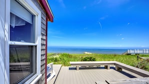 Eine Holzterrasse mit einer Bank, mit Blick auf einen Strand und einen klaren Ozean.