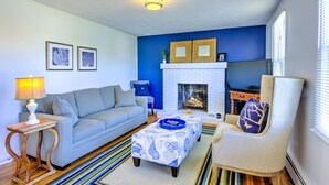 Ein Wohnzimmer mit blauer Akzentwand, einem weißen Kamin, einem Sofa, einem Couchtisch und einem Sessel.