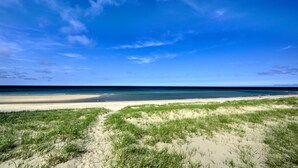 Ein Strand mit blauem Himmel und einem Sandweg, der zum Wasser führt.