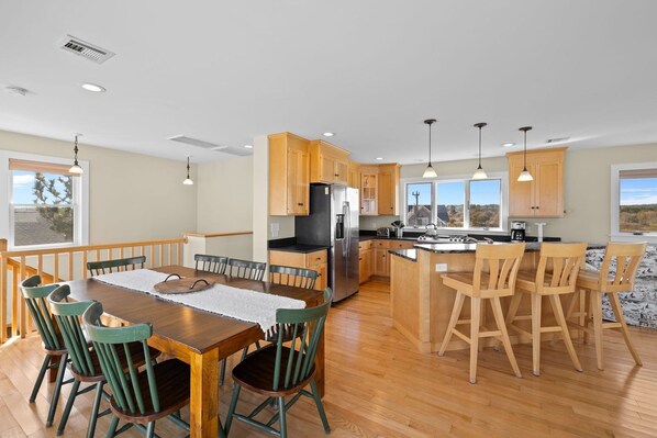 Una cocina moderna con armarios de madera, una isla central y un comedor con mesa y sillas.