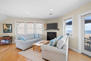 A living room with a fireplace, a sofa, a coffee table, and a television. - Oceanfront at Sagamore Beach (Sagamore Beach)