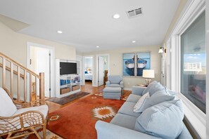 A living room with a television, seating area, and a view of the outside. - Oceanfront at Sagamore Beach (Sagamore Beach)
