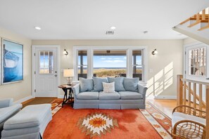 Ein Wohnzimmer mit Sofa, Teppich und Blick auf den Strand.