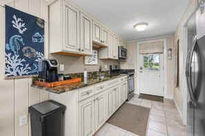 A kitchen with white cabinets, a microwave, a coffee maker, and a stainless steel refrigerator.