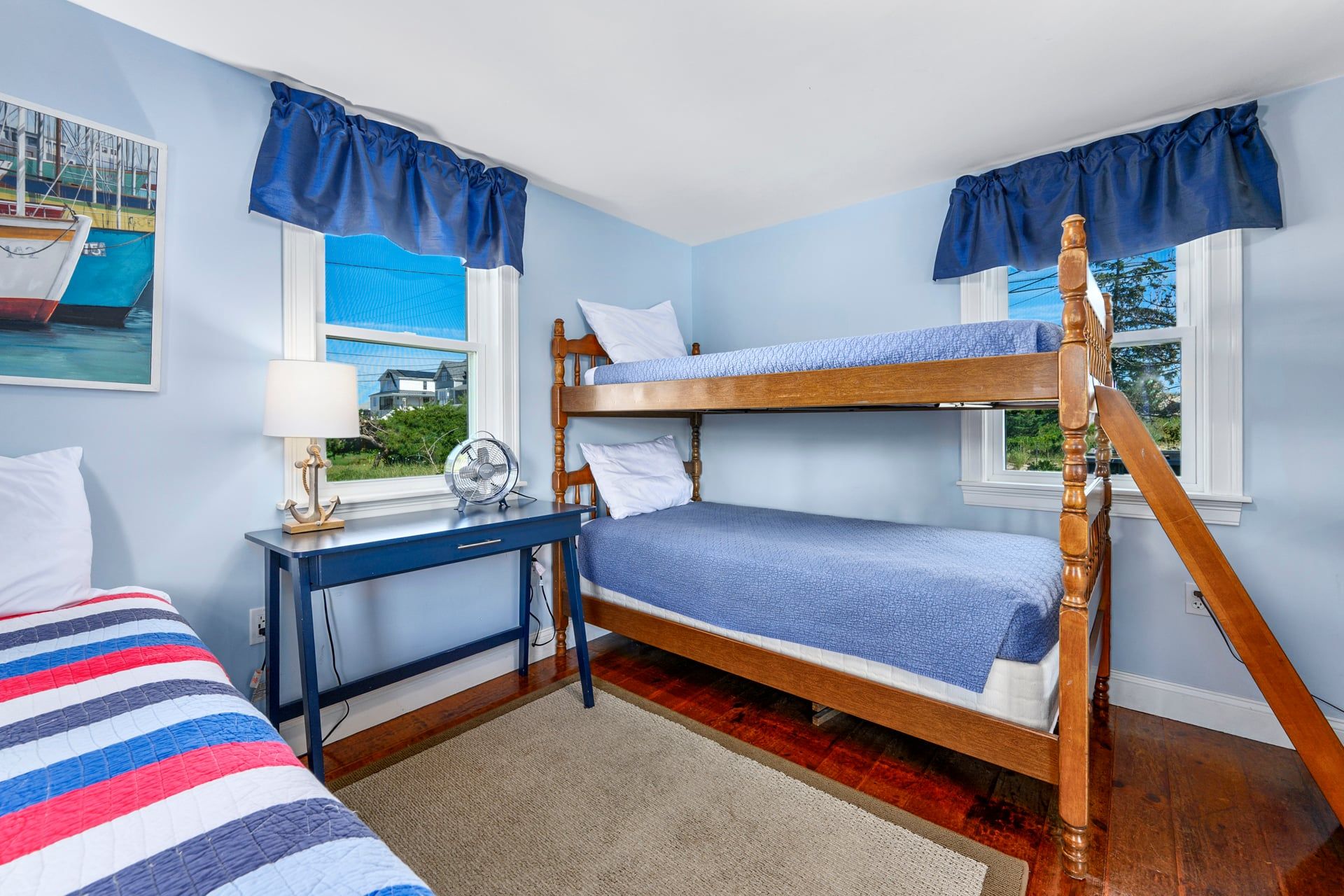 A room with bunk beds, a desk, a lamp, and a window with a view.
