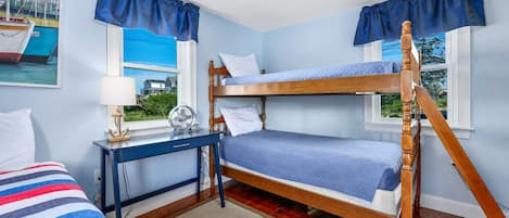 A room with bunk beds, a desk, a lamp, and a window with a view.
