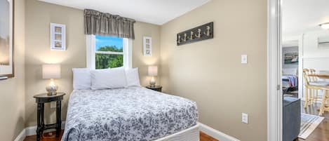 Une chambre à coucher avec un lit, des lampes de chevet, une fenêtre donnant sur un paysage agréable et une porte menant à une autre pièce.