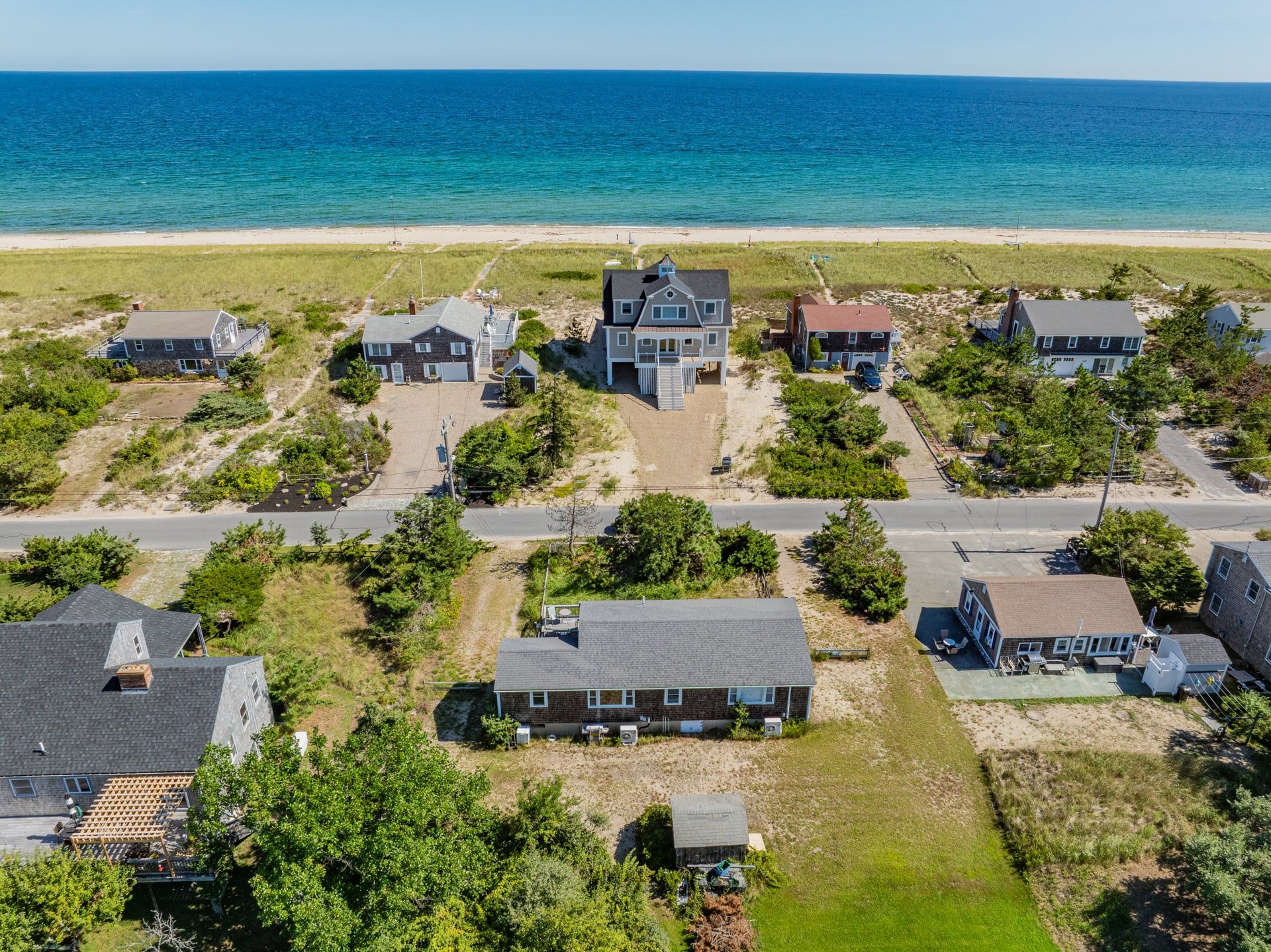 A coastal residential area with houses, a beach, and a clear sky.