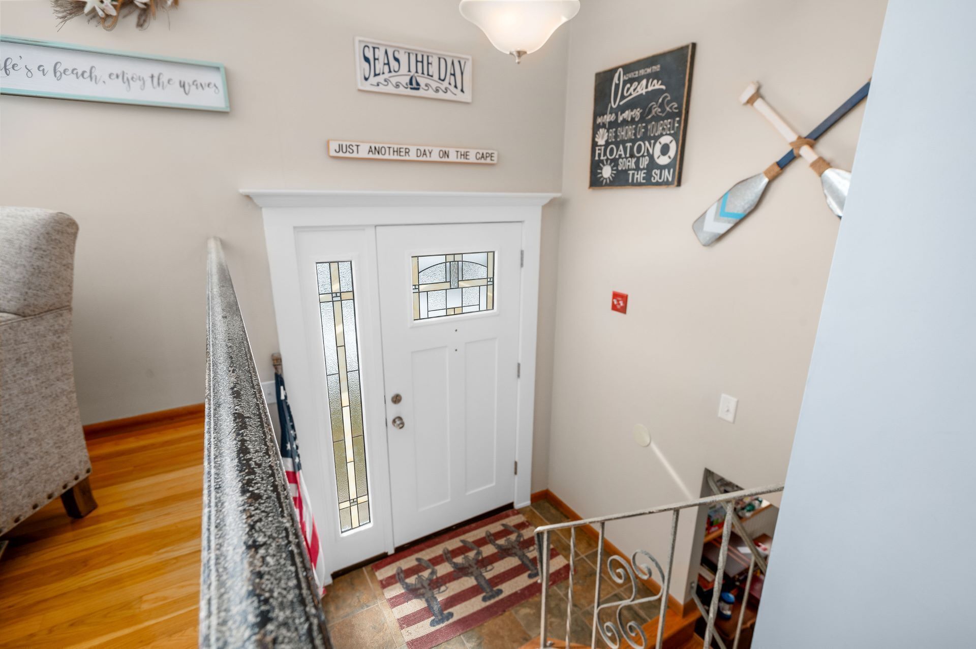 A hallway with a white door, a staircase, and a rug with a nautical theme.