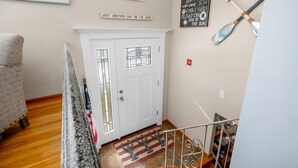Ein Flur mit einer weißen Tür, einer Treppe und einem Teppich im Seglerstil.
