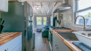 Eine kleine Küche mit Kühlschrank, Herd, Spüle und einer Holzarbeitsplatte.