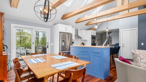 A modern kitchen with blue cabinets, a wooden dining table with chairs, and a large island.