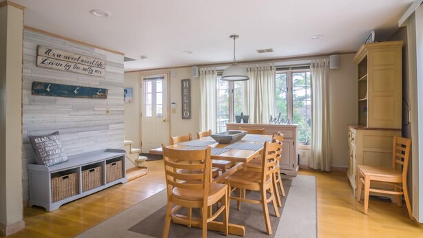 Ein geräumiger Essbereich mit Holzmöbeln, einer Tafel mit motivierenden Zitaten und Blick ins Freie durch große Fenster.