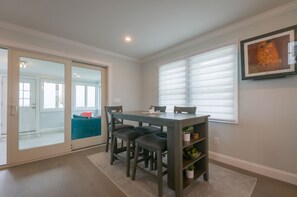 A dining area with a table and chairs, a sliding glass door leading to a balcony, and a framed artwork on the wall.