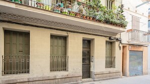 A building facade with three windows, a door, and a balcony with potted plants. - AMAZING Gran de Gràcia (08012 Barcelona)