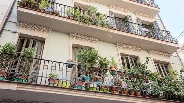 Un edifici de diverses plantes amb balcons, cadascun decorat amb plantes en testos.
