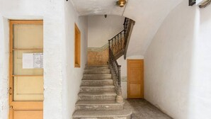 Una escala amb una porta de fusta a l'esquerra i una paret amb una làmpada penjant a sobre.