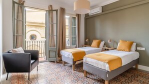 Habitació d'hotel amb dos llits, una cadira, un balcó i un paviment amb dibuixos.