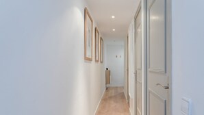 A hallway with white walls, wooden flooring, and doors on the right.