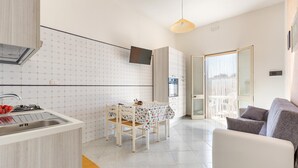 A modern kitchen with a dining table, a sofa, and a TV mounted on the wall. - 2048 Casa Marchello - Bilo 2 by Barbarhouse (Castrignano del Capo)