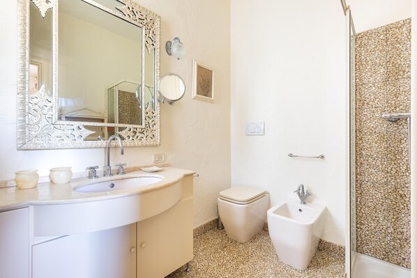 Un baño con lavamanos blanco, un espejo grande, inodoro y bidé.