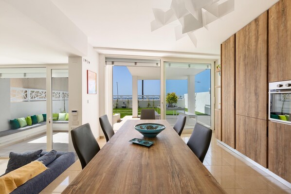 A modern kitchen with a wooden dining table, black chairs, and a decorative bowl.