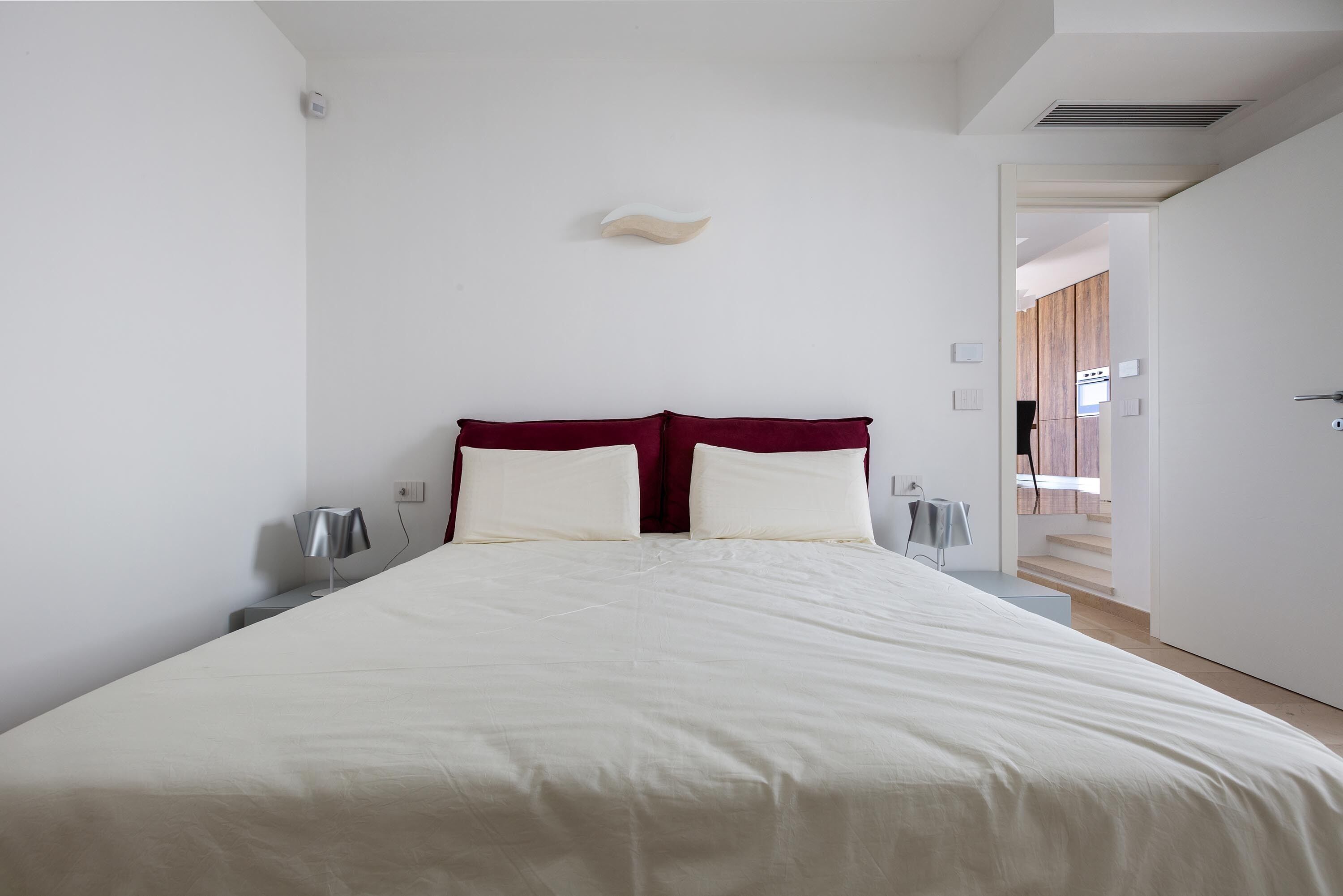 Una camera da letto moderna con un letto grande, una testiera in legno e una parete bianca.